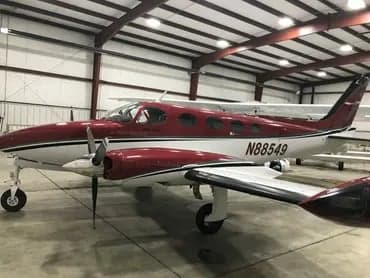 A maroon and white Cessna 340A aircraft with tail number N88549 is parked inside a hangar.