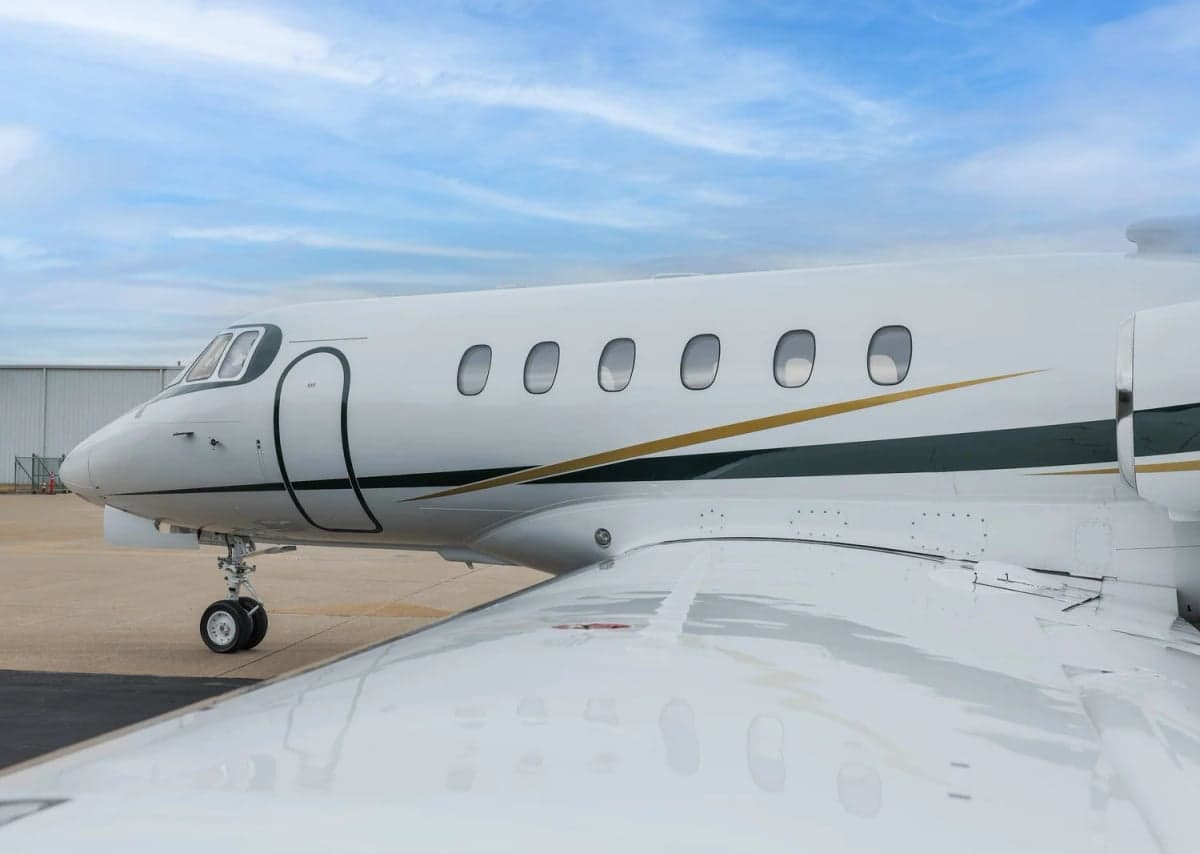 Close up of the front of a Hawker 800XP with a white and gold paint scheme.