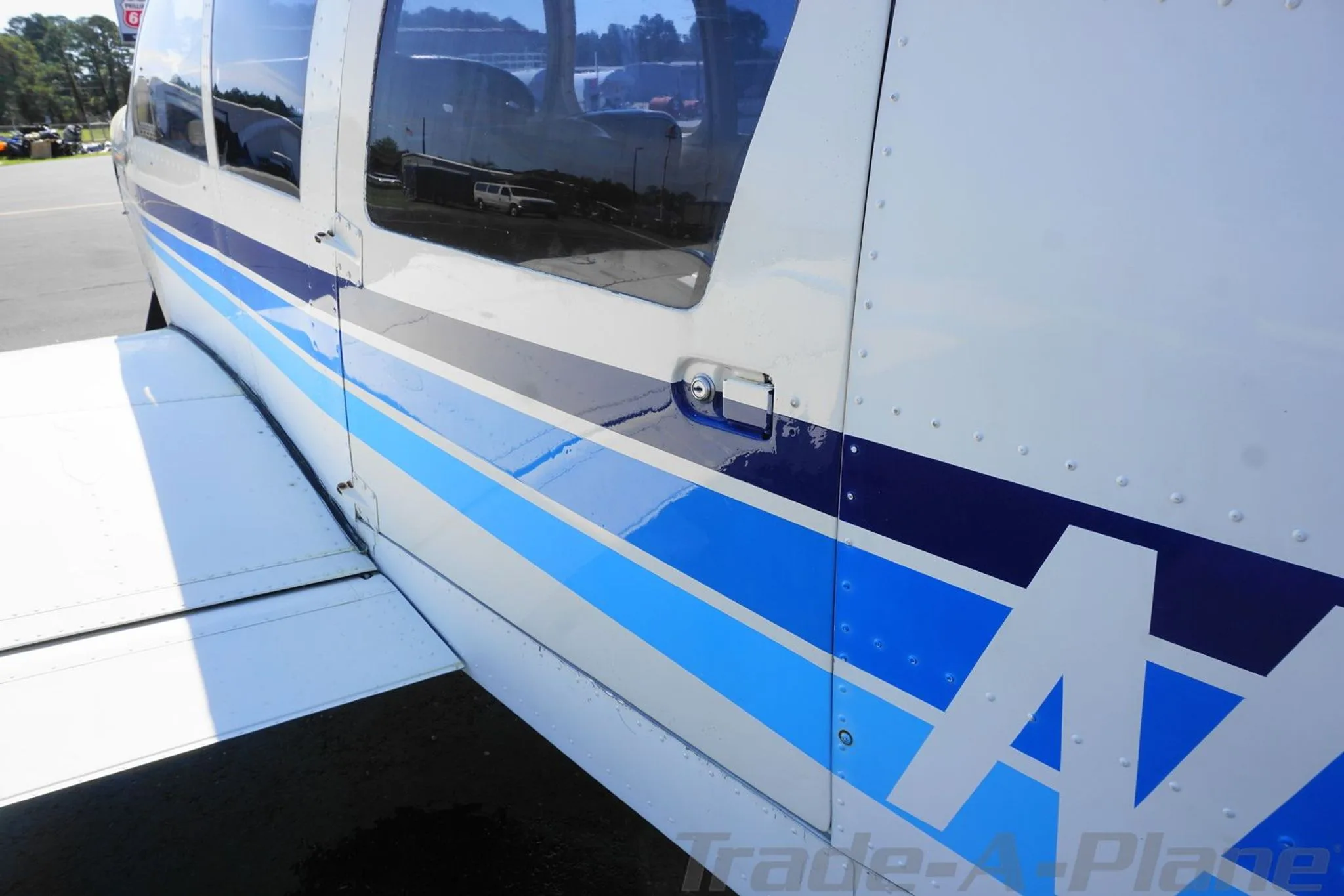 Close-up of the aircraft's side showing blue stripes, passenger windows, and wing root.