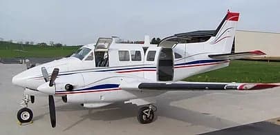 A twin-engine aircraft with an open door on the ramp.
