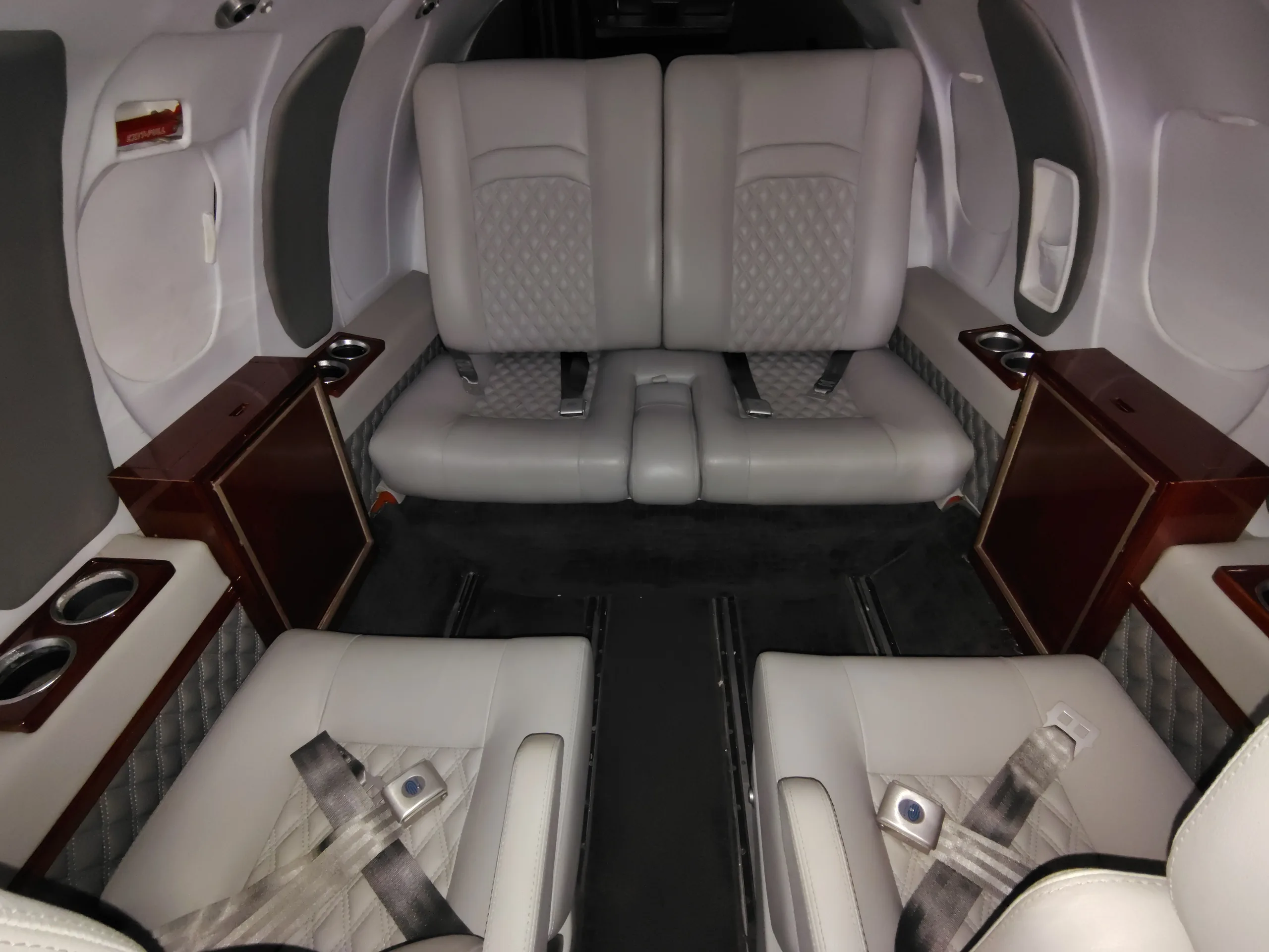 The aircraft cabin interior featuring light gray quilted leather seats and dark carpet.