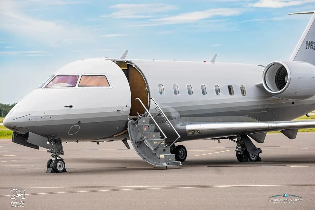 A Challenger aircraft with registration N825SG is parked on the tarmac with the door open.