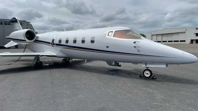 Learjet on the tarmac with a white and blue paint scheme.