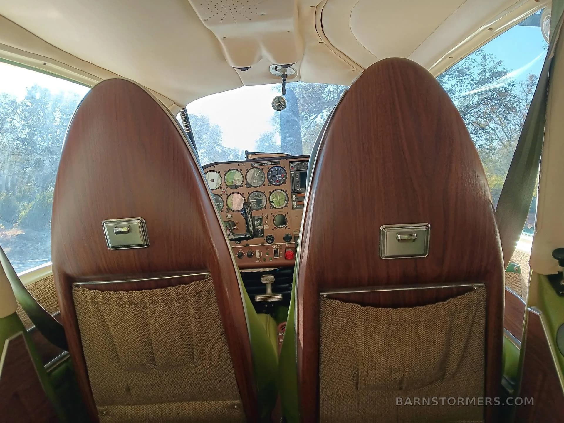 View from the rear seats looking forward into the cockpit, showing the wooden backs of the front seats.