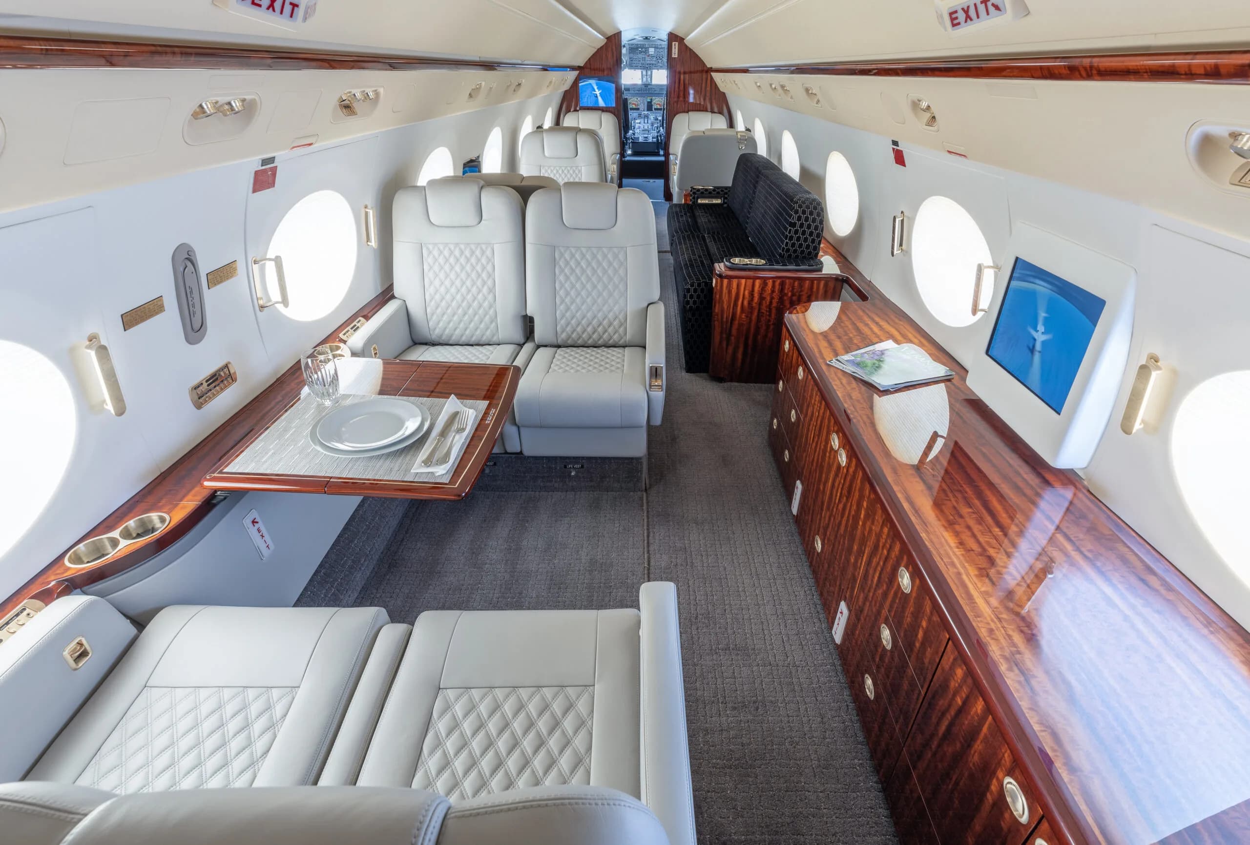 View of the aircraft interior with white leather seats and wood trim.