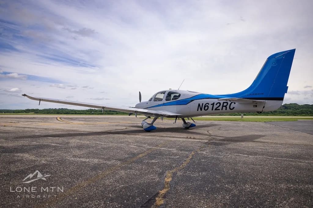 A silver and blue Cirrus SR22T Carbon aircraft, registration N612RC, parked on an airfield.