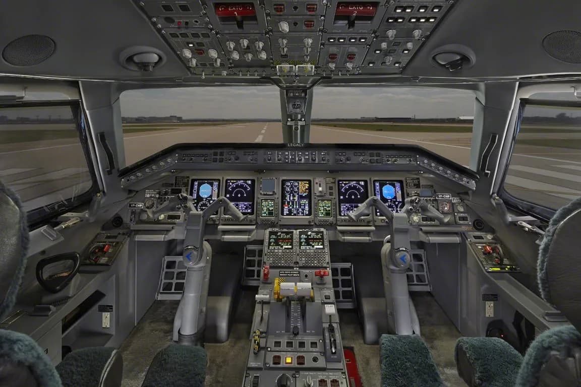 The cockpit of an Embraer Legacy 650 business jet with multiple display screens and controls.
