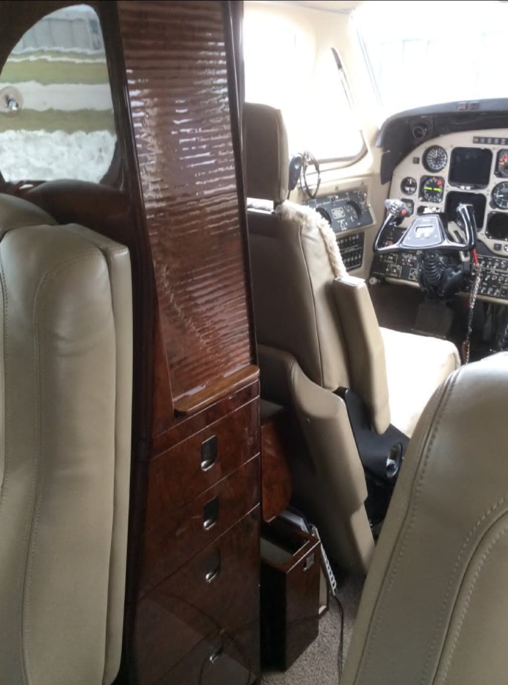 View of the aircraft cabin with a wooden cabinet and cockpit.