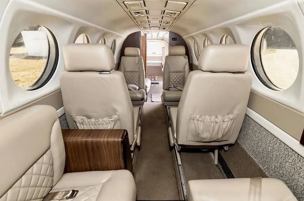 Cabin view of a Beechcraft King Air 360ER with tan leather seats and wood accents.