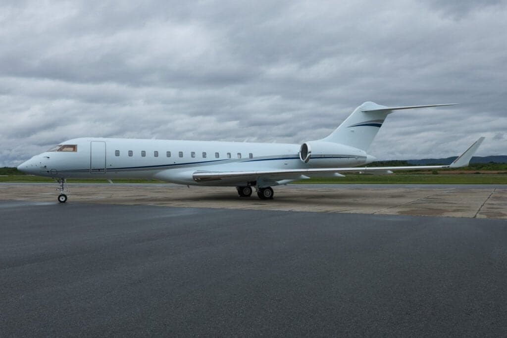 A Bombardier Global Express aircraft is parked on the tarmac on a cloudy day.