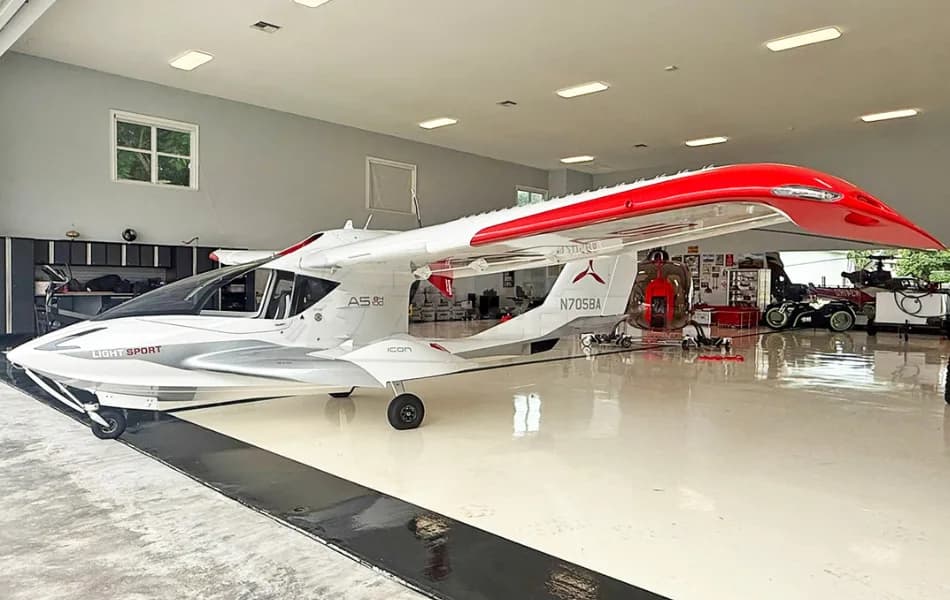 A white and red ICON A5 amphibious light sport aircraft is parked inside a clean hangar.
