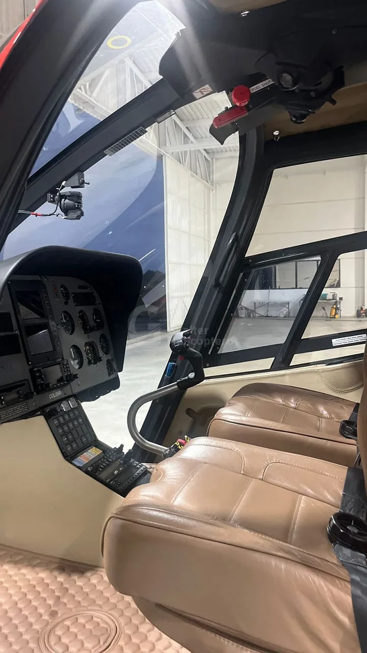 The cockpit of a helicopter features a beige instrument panel and brown leather seats.
