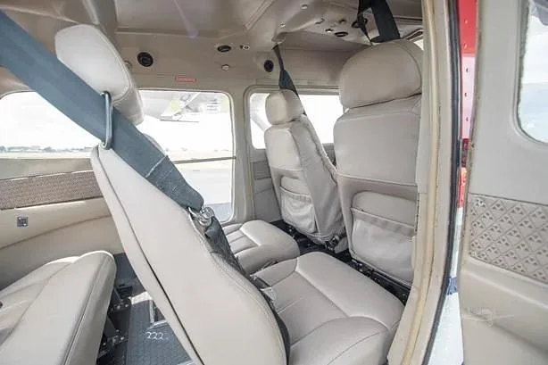 A view of the light tan interior seats of a small aircraft, looking towards the rear from the front.