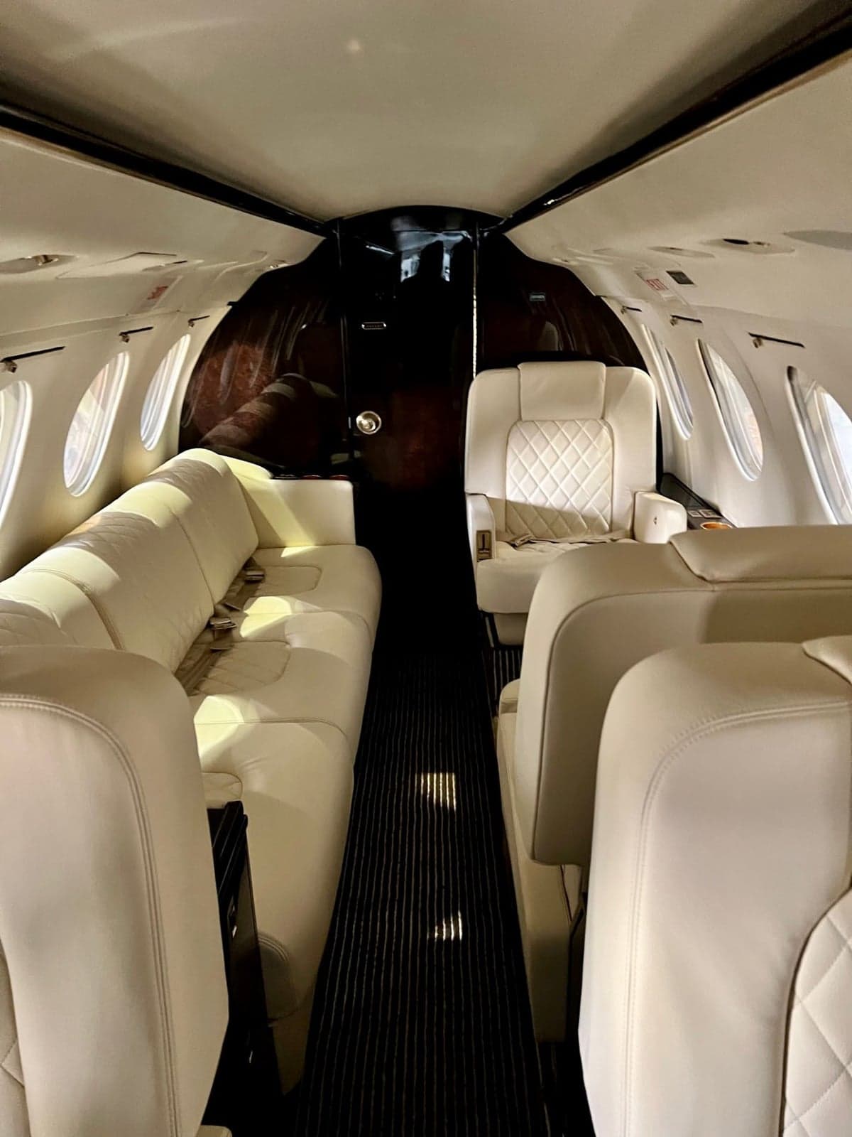 The interior of a Dassault Falcon 900 features a white leather seat with diamond stitching.