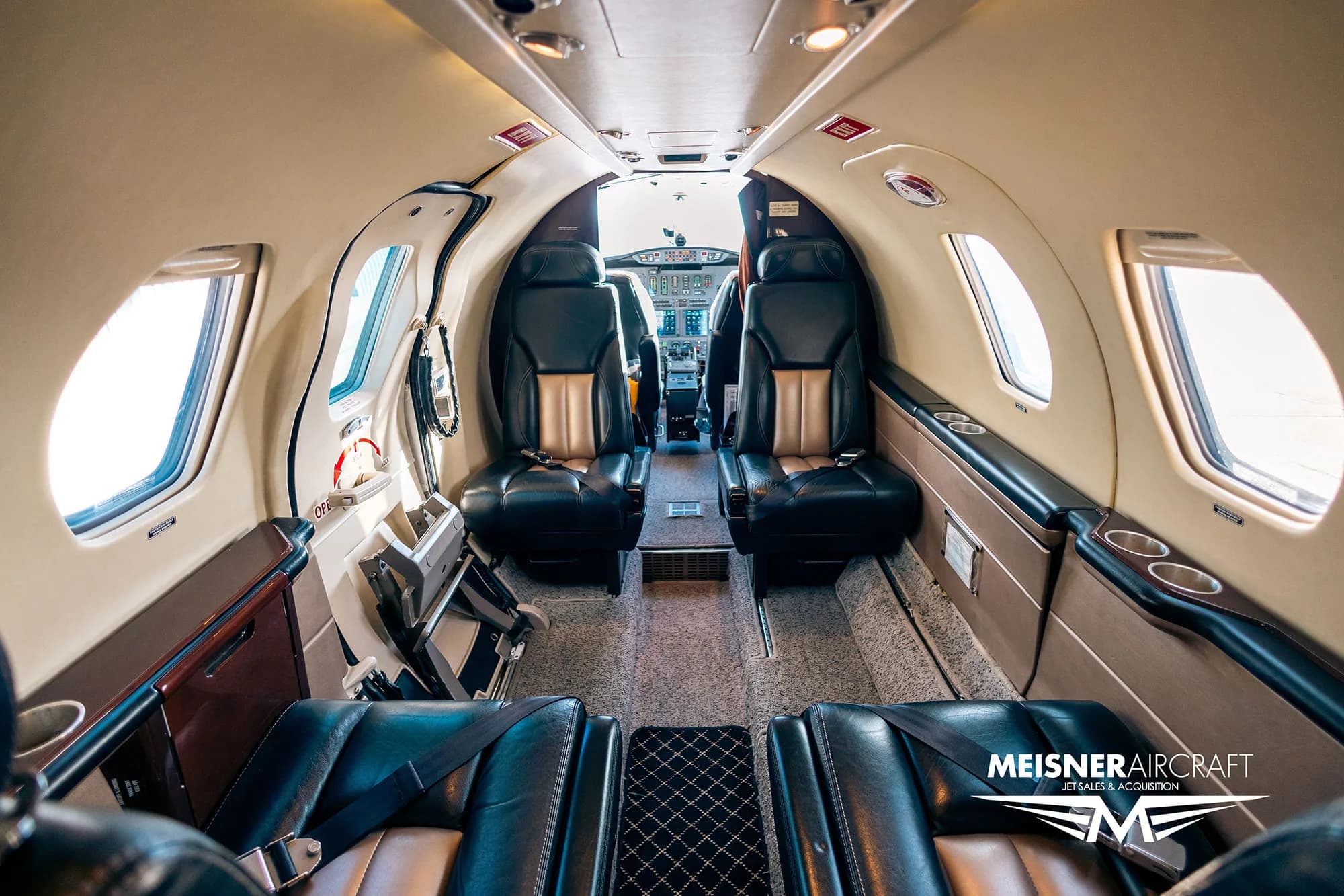 View of the aircraft interior from the rear, showing seats and cockpit.