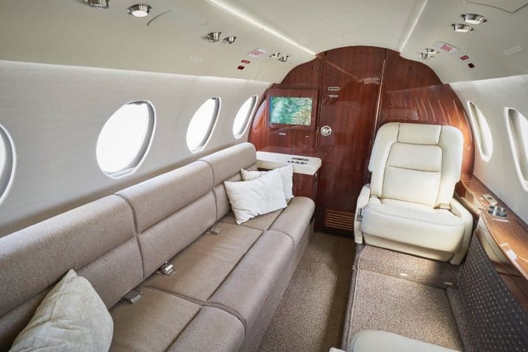 Interior view of the aircraft cabin with a couch and cream-colored leather seat.