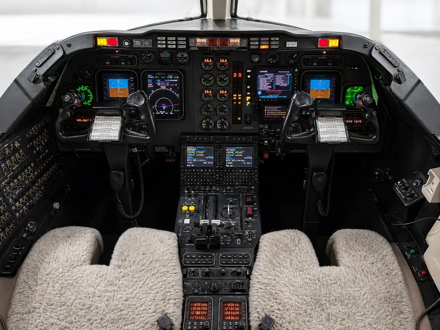 The aircraft cockpit features a complex array of digital displays, analog gauges, and controls, with two pilot seats.