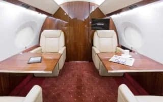A seating area with two seats and tables inside the aircraft.