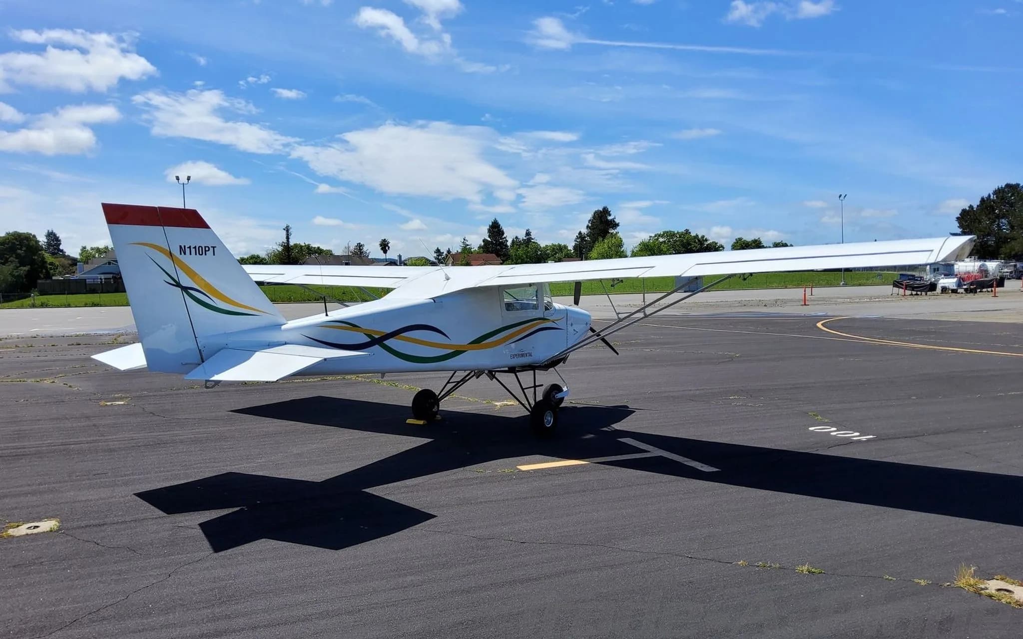 A white BushCaddy aircraft with "N110PT" on the tail, viewed from the rear-right on a sunny tarmac.