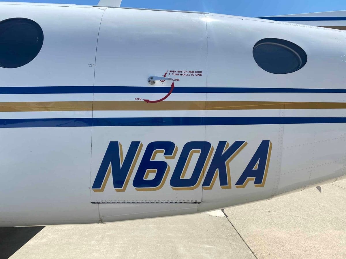 A close-up of the fuselage of the Beechcraft King Air 350, showing the N60KA registration and blue and gold stripes.
