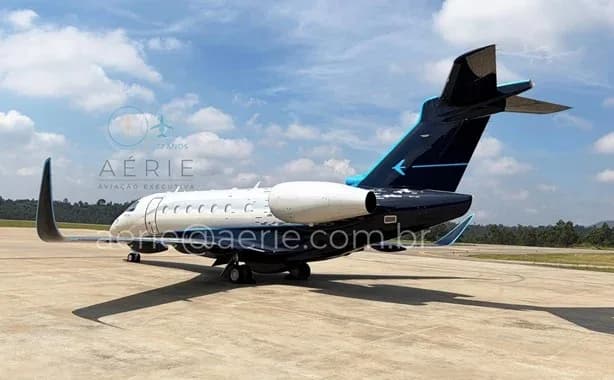A rear view of the white and dark blue Embraer Praetor 600 business jet parked on a tarmac.