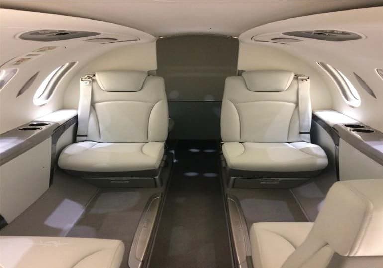 The aircraft's interior features white leather seats and a spacious cabin.