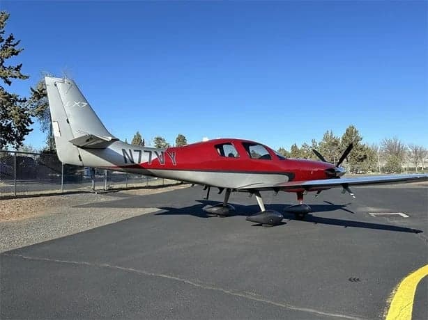 A red and silver LX7 aircraft is parked on the tarmac.