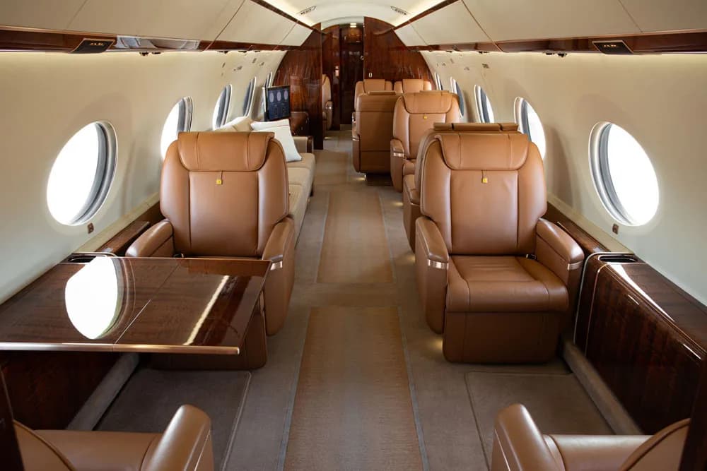 Aircraft cabin with leather seats and a table.