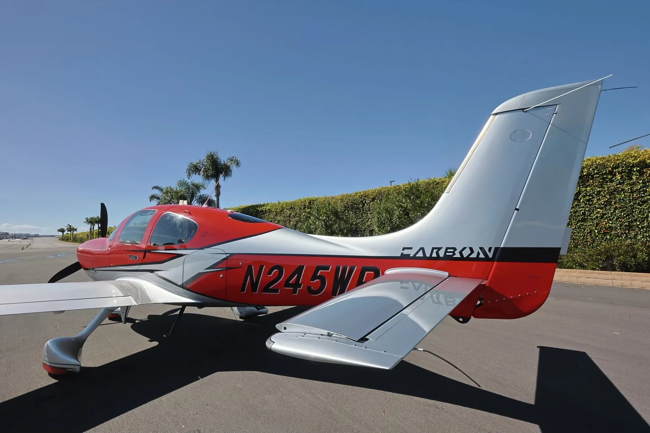 A rear-side view of the red and silver Cirrus SR22 GTS aircraft, N245WP, highlighting the tail section.