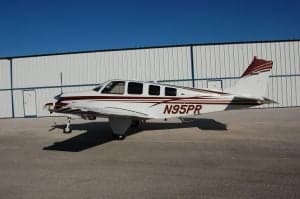 A Beechcraft Bonanza sits on the tarmac, showing the tail number.