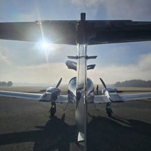 Rear view of a silver and blue Diamond DA62 aircraft on the tarmac.