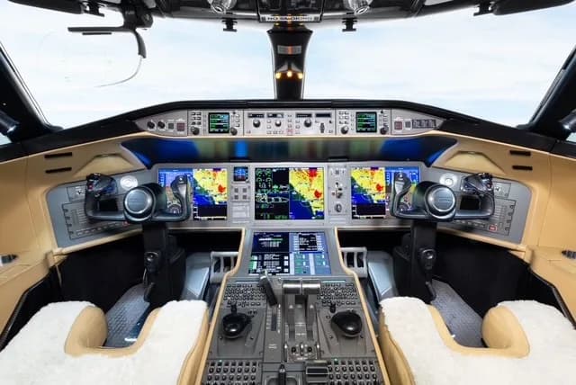 The modern cockpit of a business jet, featuring multiple large digital displays and a complex control panel.