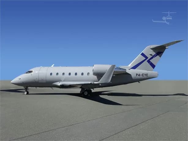 A light grey Bombardier Challenger 604 business jet with a blue tail logo, parked on an airfield under a clear blue sky.