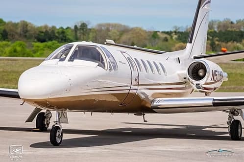A white and brown Cessna Citation business jet, tail number N511AB, is parked on an airfield.