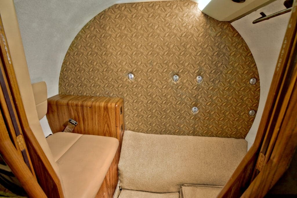 Rear seating area of the Citation Ultra cabin with a small seat and storage compartment.