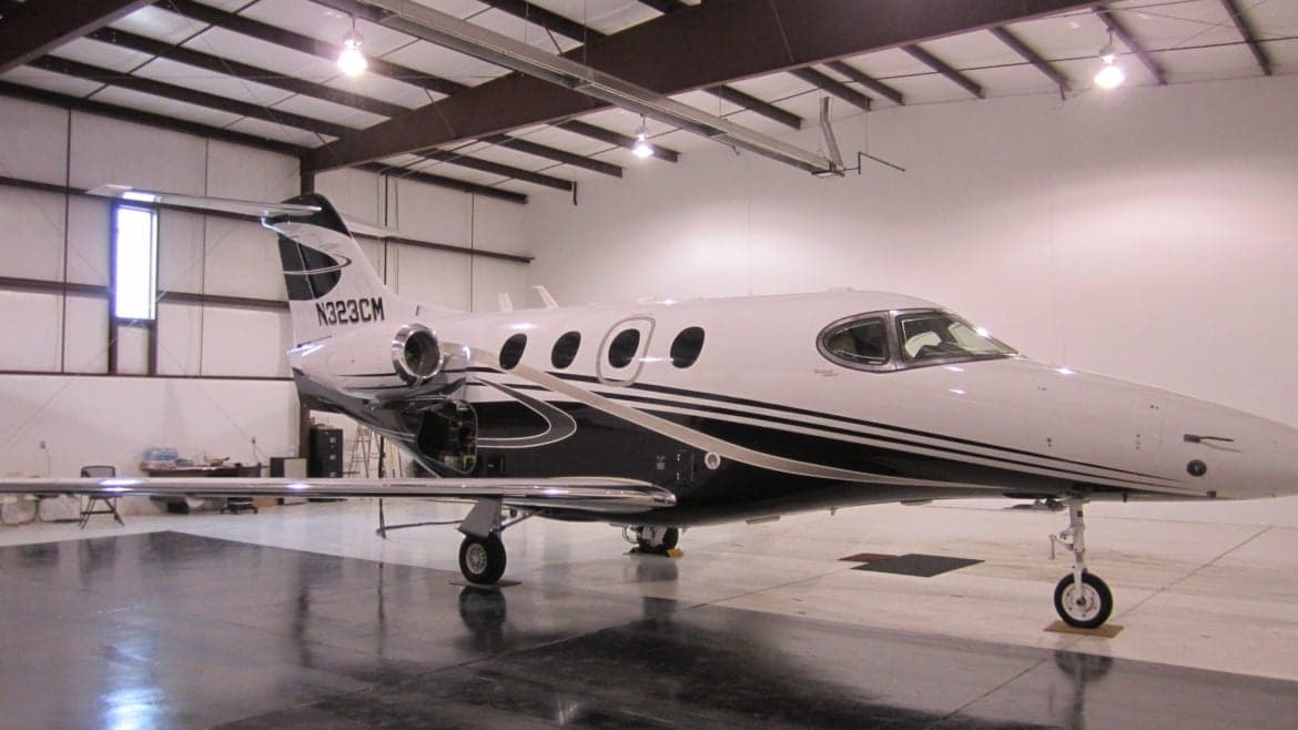 A side view of a jet with a black and white paint scheme inside a hangar.