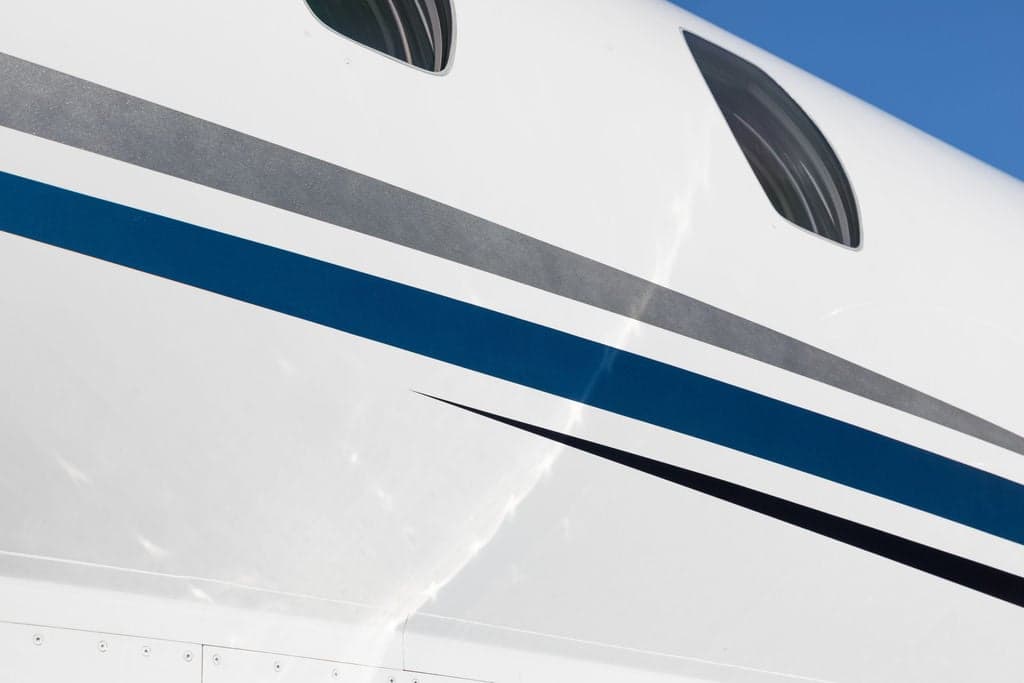Close-up of the fuselage of a Cessna Citation CJ3+ aircraft, showing the paint scheme and windows.