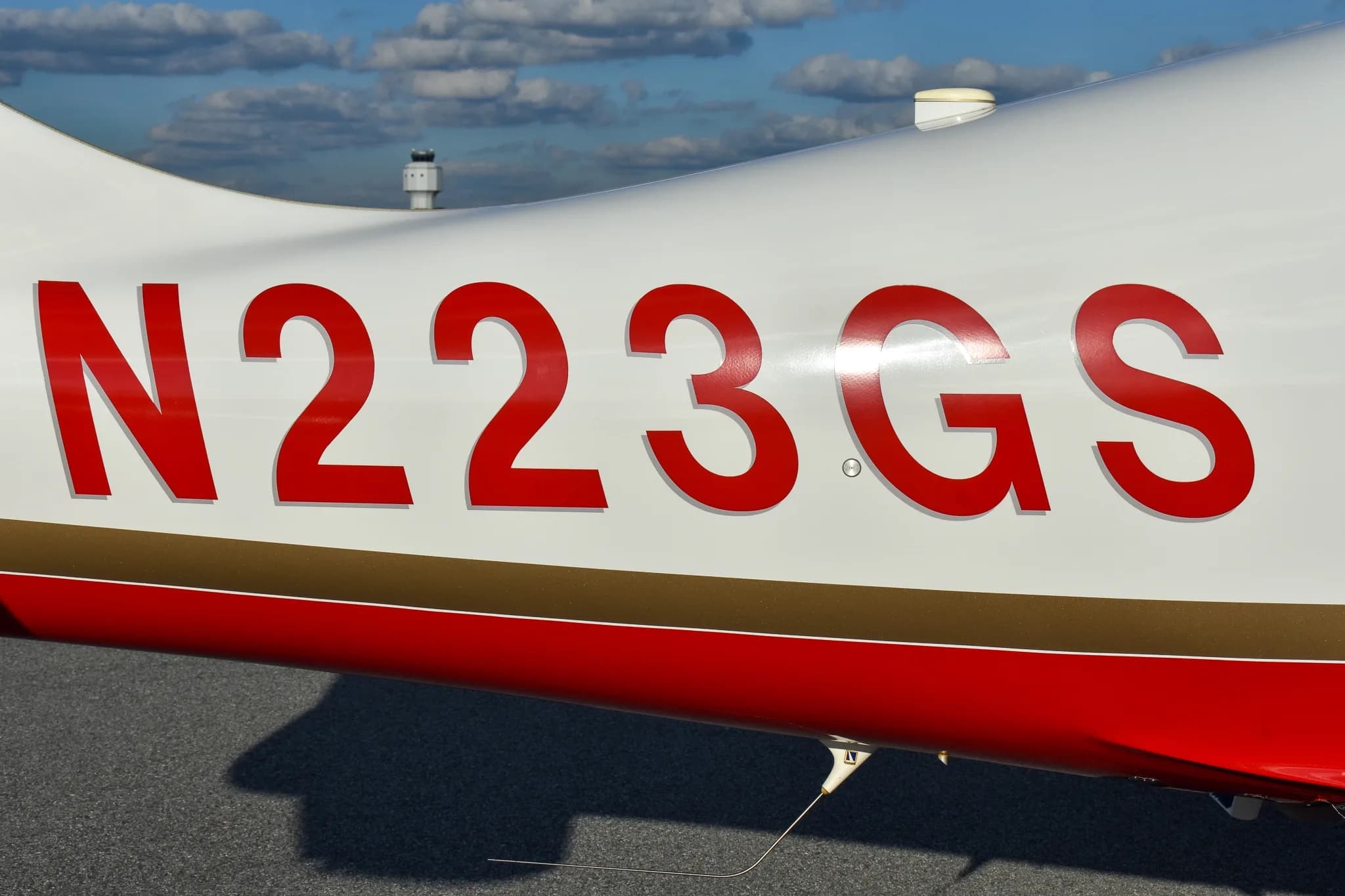 Close-up of the red tail number N223GS on the white fuselage of the aircraft, above a gold and red stripe.