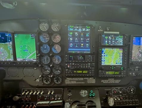 The cockpit instrument panel of an aircraft, featuring multiple digital displays and analog gauges.