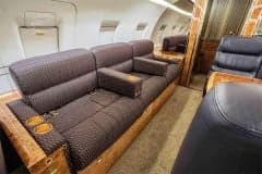 Interior of the Challenger aircraft cabin with a sofa and leather seats.