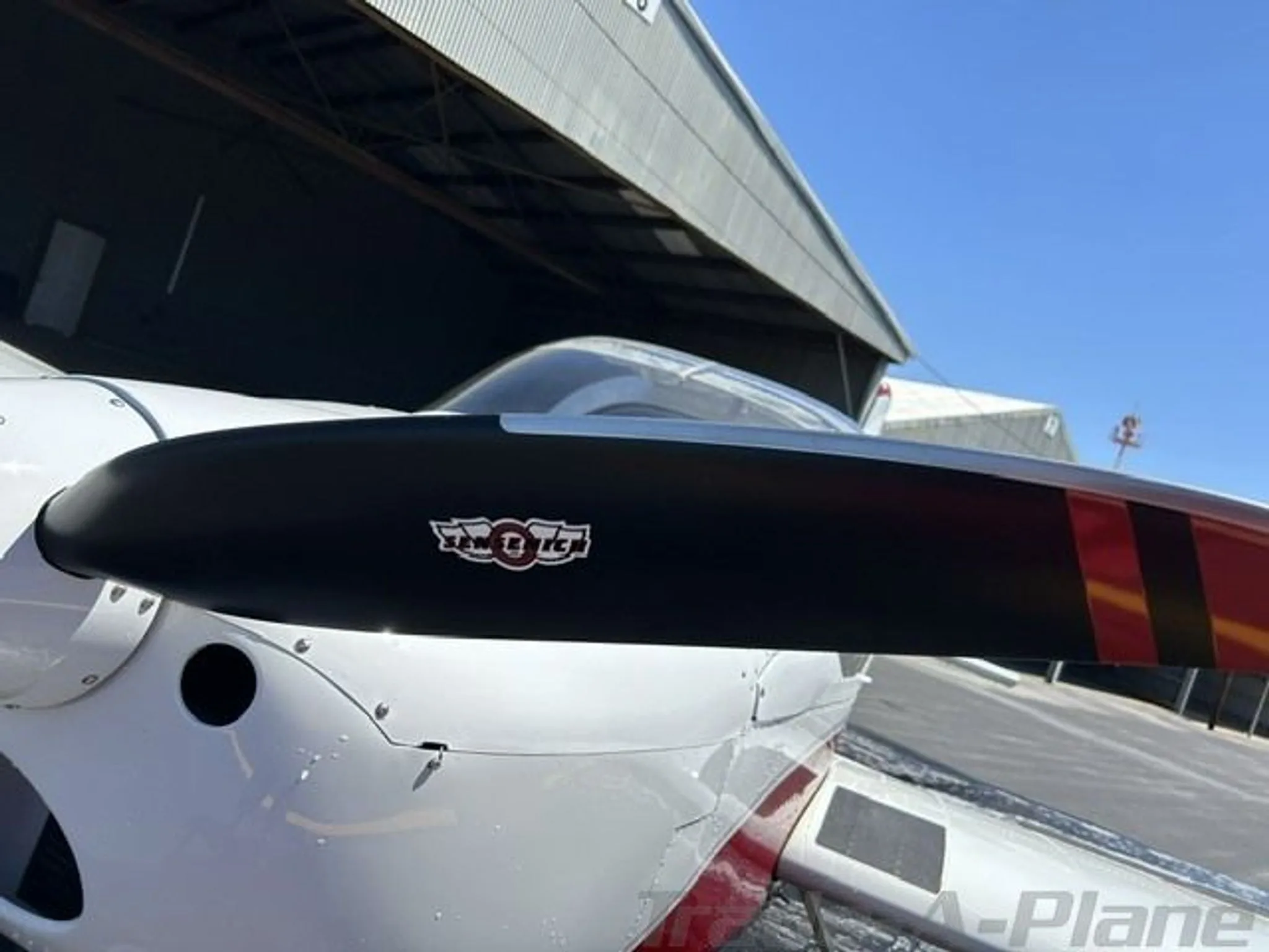 A close-up of the black propeller and nose of the white and red Van's RV-12 aircraft.