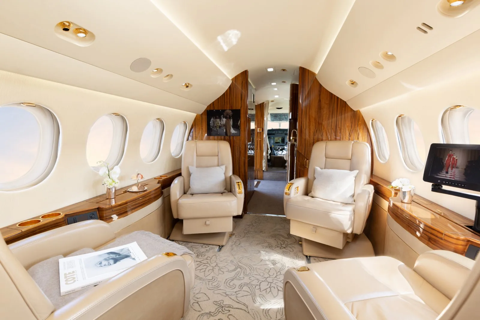 Interior of the aircraft with leather seats, wooden accents, and a view towards the cockpit.