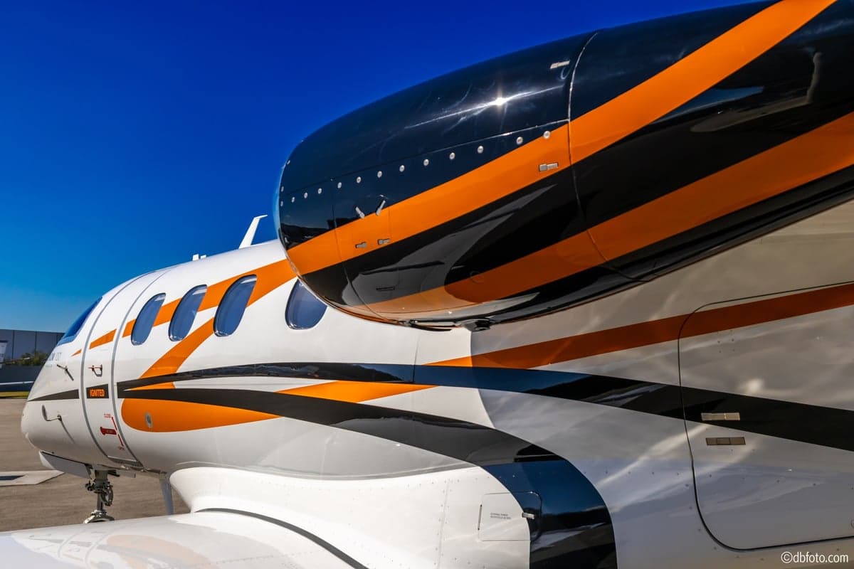 Close-up of the engine and paint scheme on a Phenom 100 aircraft.