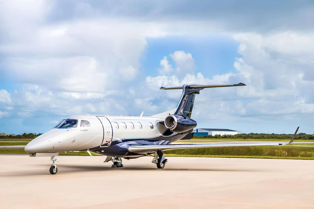 A white and blue Embraer Phenom 300E on the tarmac.