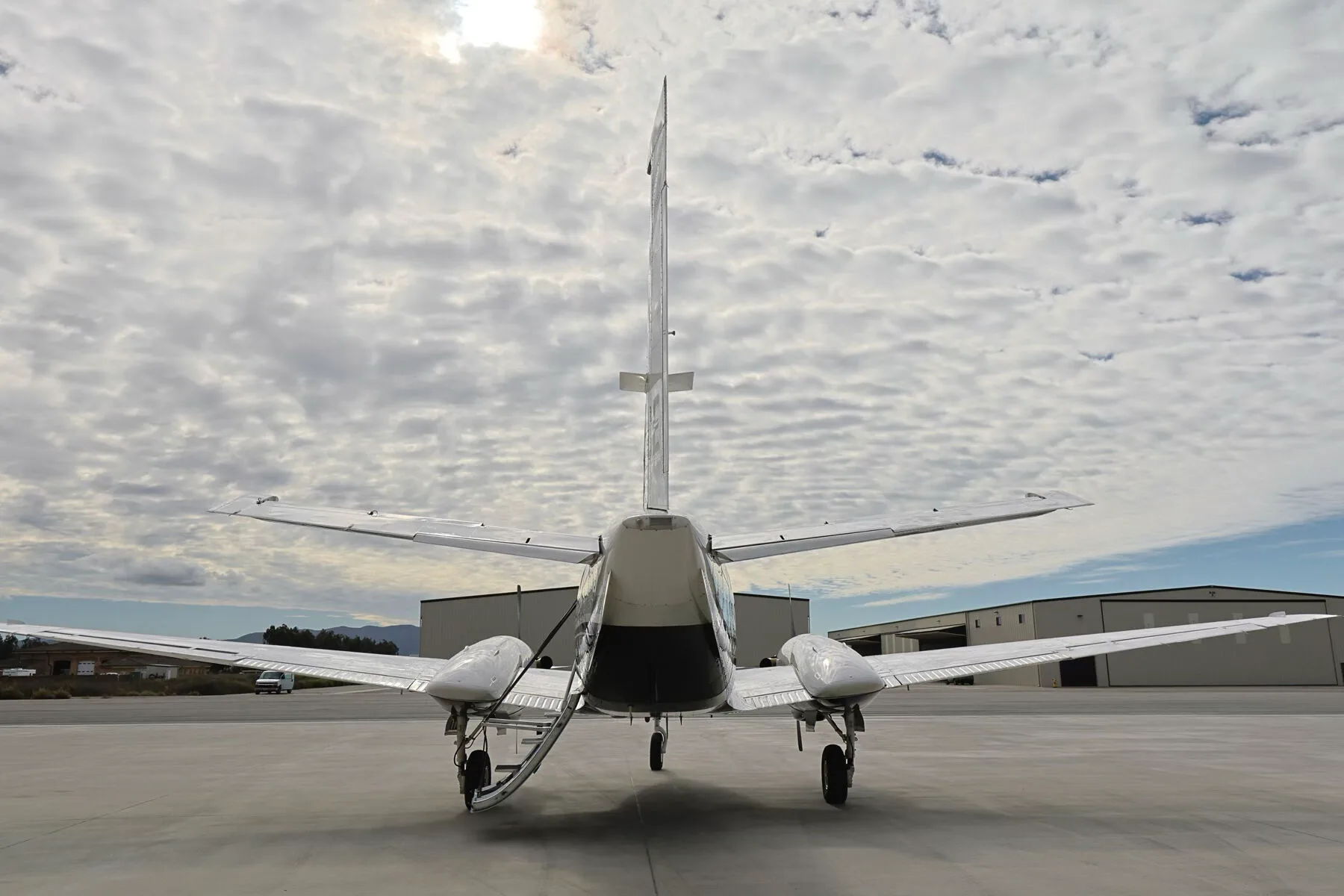 A rear view of the N77CE twin-engine turboprop aircraft on an airfield.