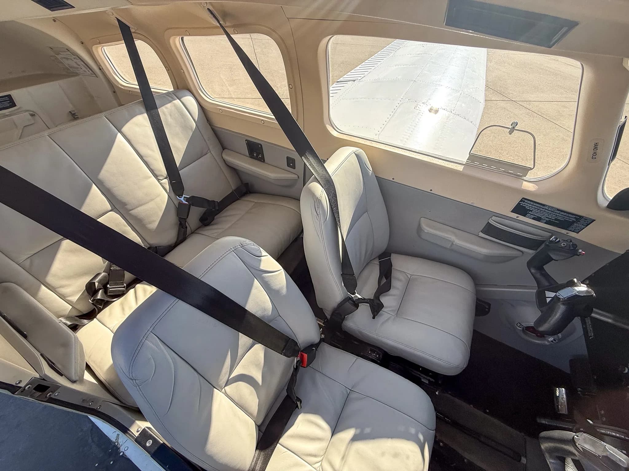 The light gray leather interior of a Piper Archer TX cabin, showing both front and rear seats.