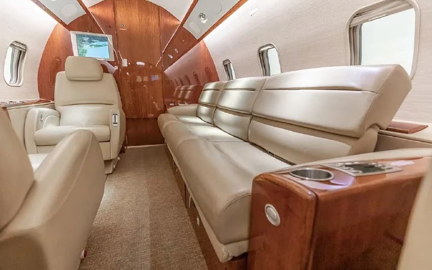 A view of the Challenger 350 cabin with beige leather seats and a couch.