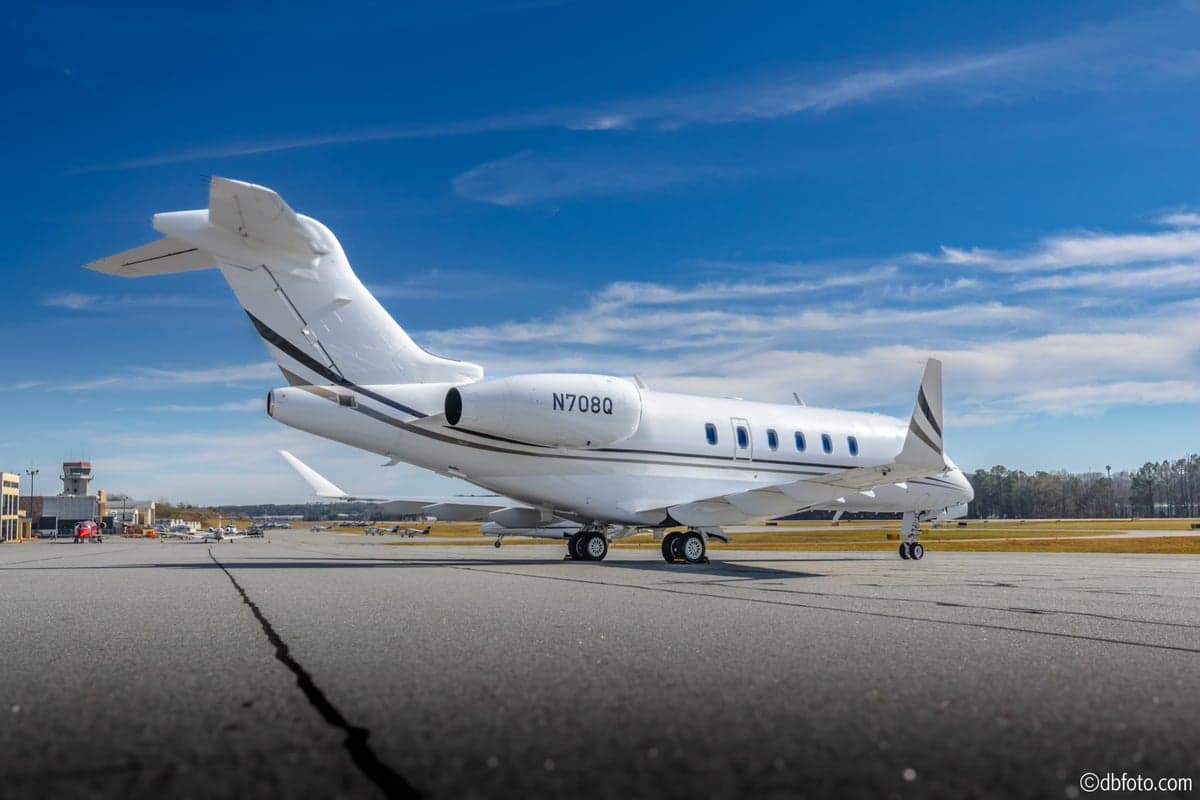 A low-angle rear view of the white Bombardier Challenger N708Q business jet on an airport tarmac.