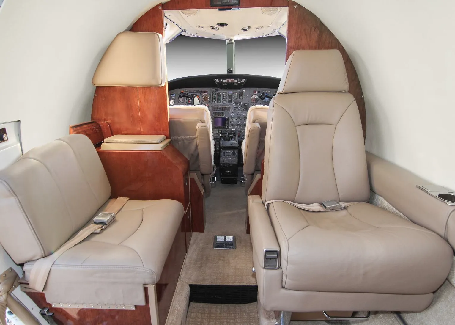 Interior view of the aircraft cabin with leather seats and wood accents.