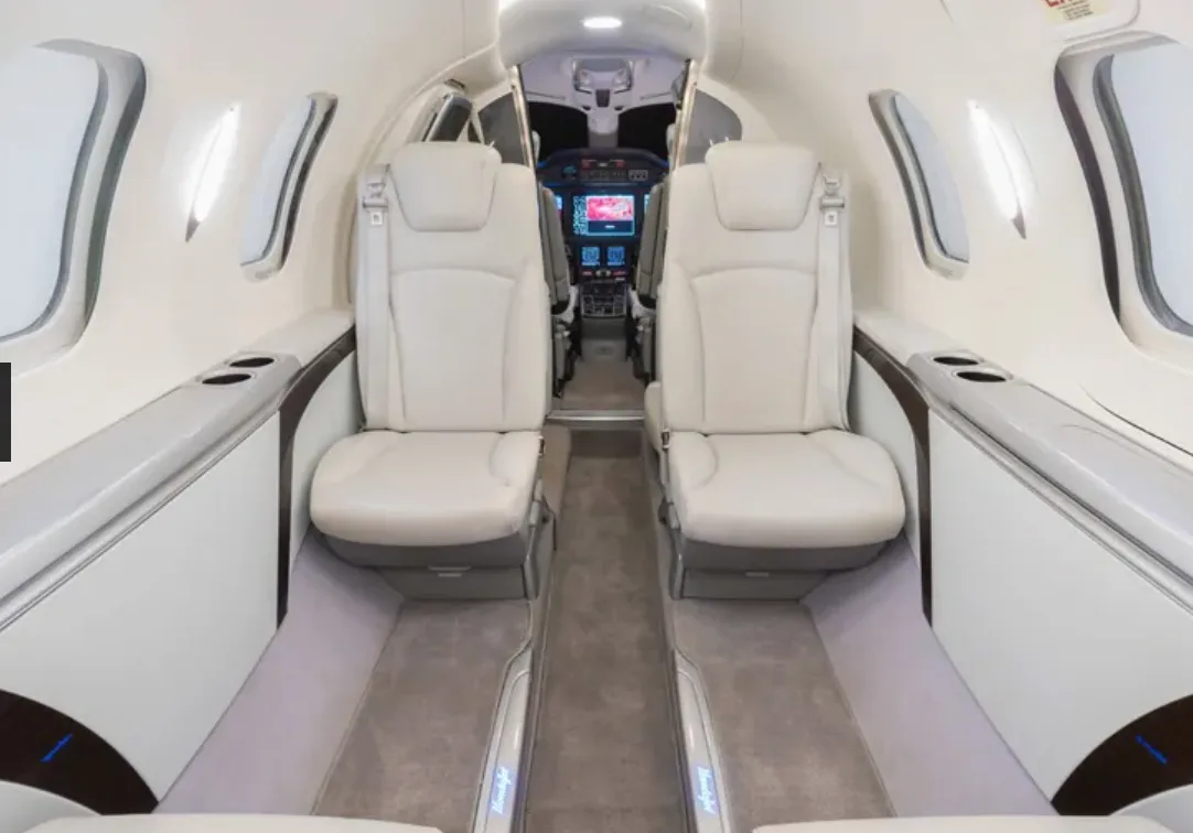 The interior cabin of a HondaJet, showing two rows of light-colored leather seats facing forward.